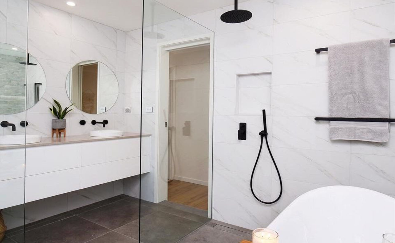 bathroom with two mirror and bathtub with glass divider